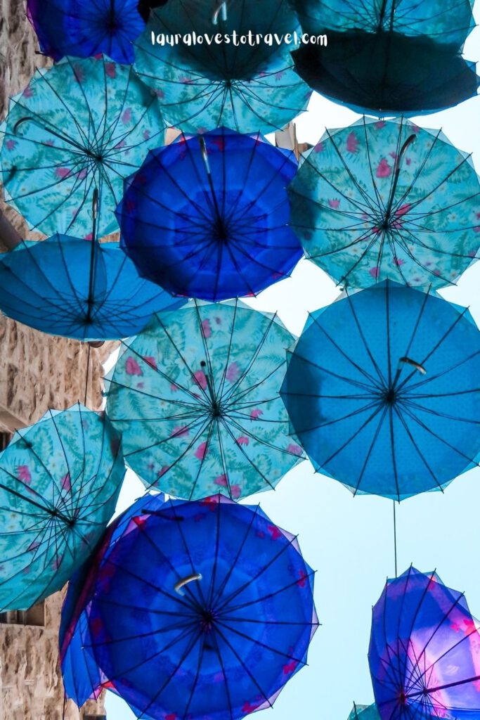 Uitgeklapte blauwe paraplu's hangen als versiering boven een straatje in Amman, Jordanië