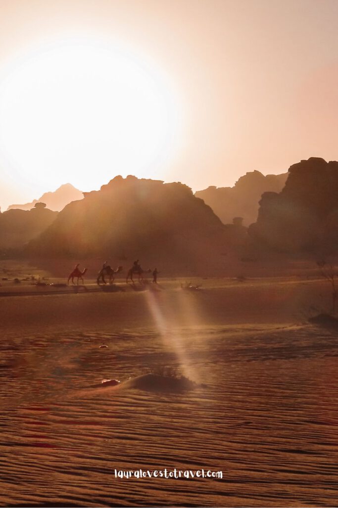 Mensen rijden op kamelen tijdens de zonsondergang in de Wadi Rum woestijn, Jordanië