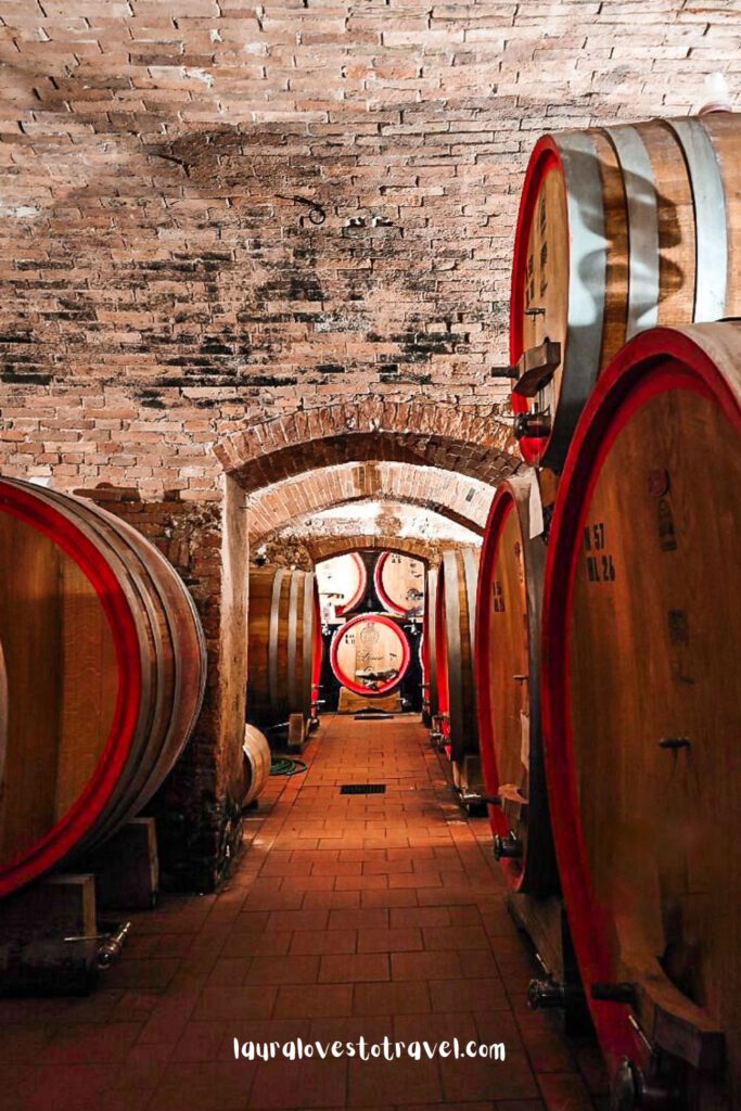 Wine barrels in a wine cellar in Montepulciano, the perfect place to taste wine during your Italy road trip